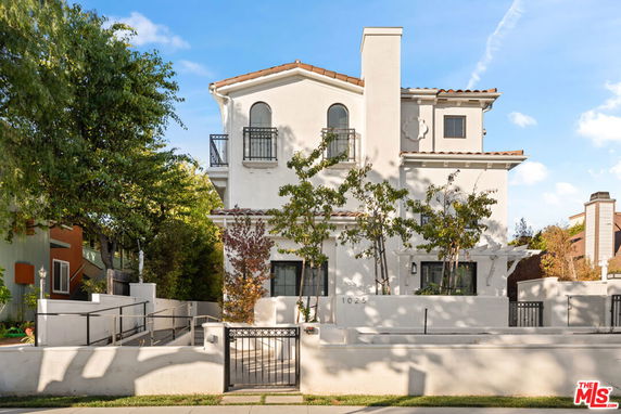 Front view of a multi-story house with a balcony and white exterior.