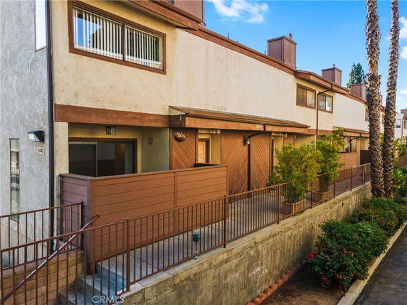 Front view of a multi-story townhouse with a fenced patio area.