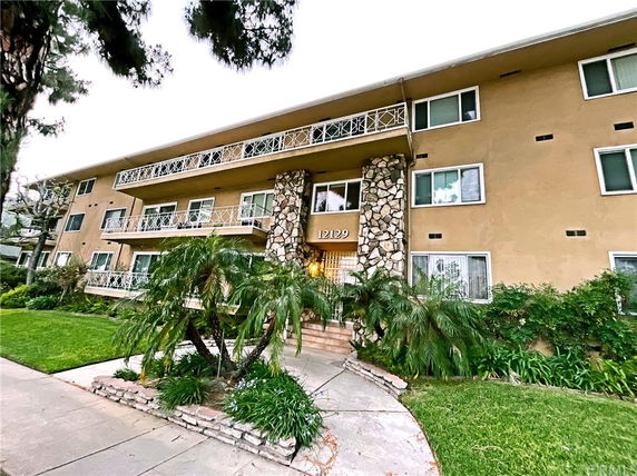 Front view of a three-story building with balconies and stone columns.