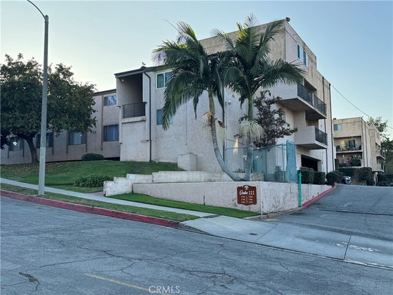 Front view of a multi-story apartment building on a sloped street.