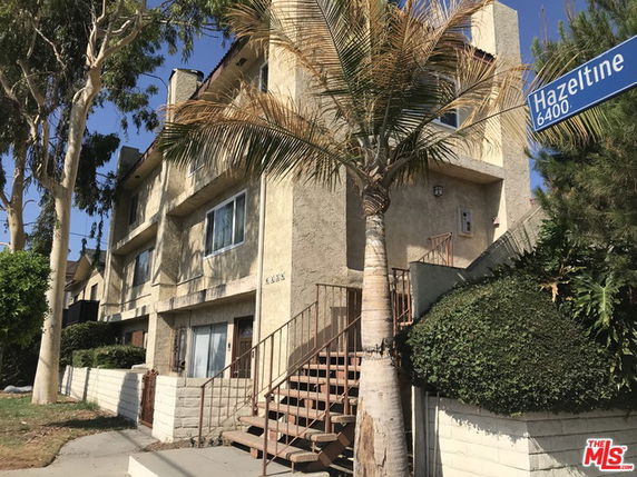 Front view of a multi-story residential building with balconies and a staircase entrance.
