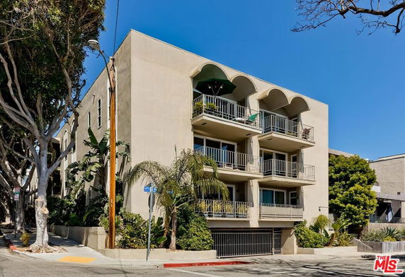 Front view of a multi-story apartment building with balconies and arched details.