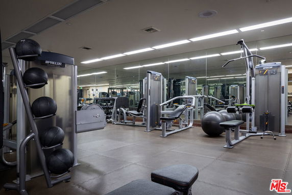 Interior view of a gym with workout equipment and mirrored walls.