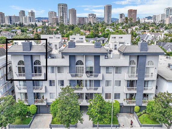 Front view of a multi-story apartment building with balconies and a gray facade.