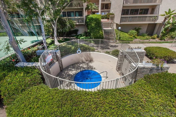 Outdoor circular hot tub surrounded by a fence in a residential area.