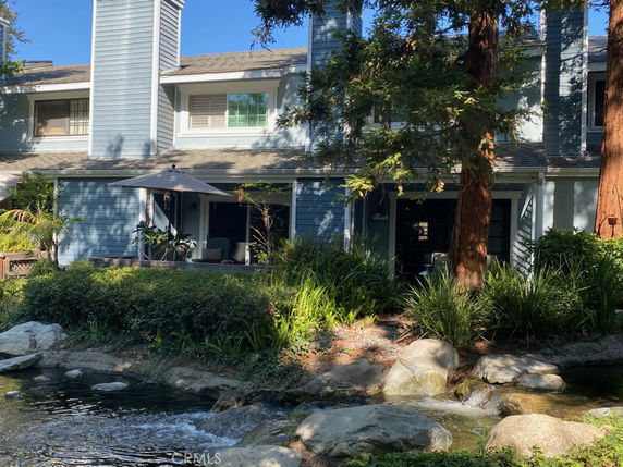 Front view of a two-story house with a chimney and patio umbrella.