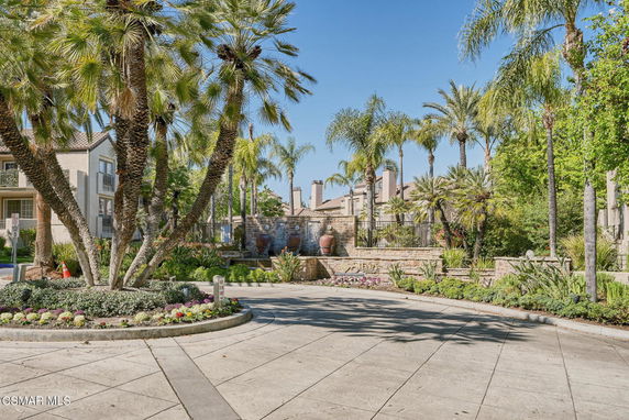 Front view of a residential complex with palm trees and a stone entrance.