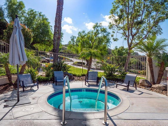Outdoor hot tub area surrounded by lounge chairs and tropical plants.