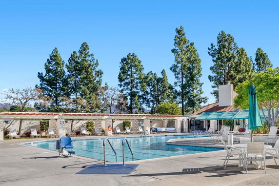 Outdoor swimming pool area with lounge chairs and umbrella seating.
