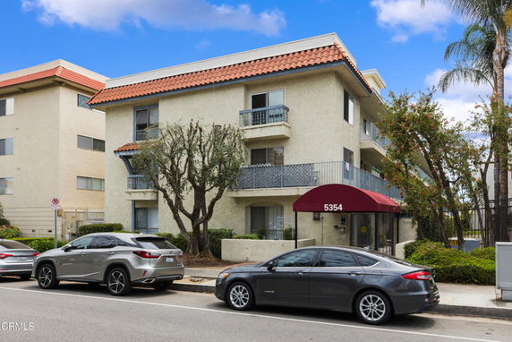 Front view of a multi-story building with balconies and a red canopy entrance.