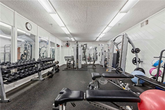 Indoor gym facility with various exercise equipment including weights and machines.