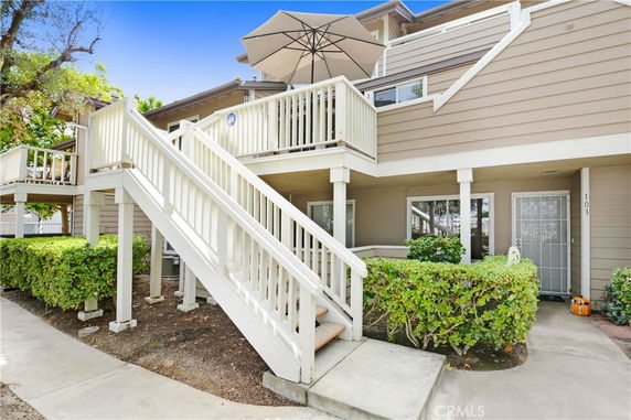 Front view of a two-story house with an external staircase and balcony.
