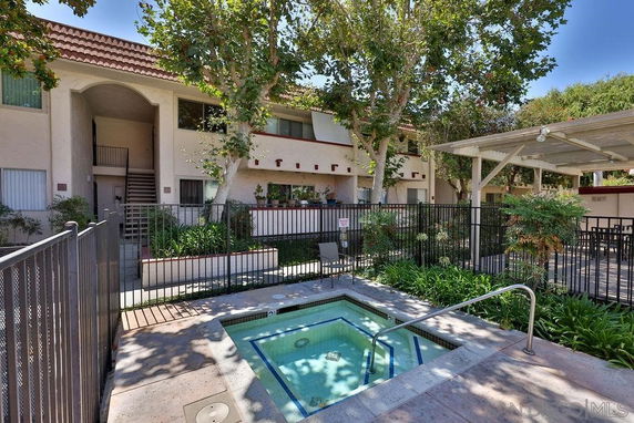Outdoor area with a small swimming pool in front of a two-story residential building.