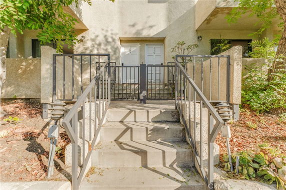 Front view of a building with two white doors and a staircase leading up with metal railings.