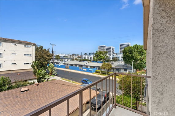 View from a balcony showing a street, nearby buildings, and distant high-rise structures.