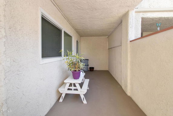 Covered outdoor area with a small table and potted plant.