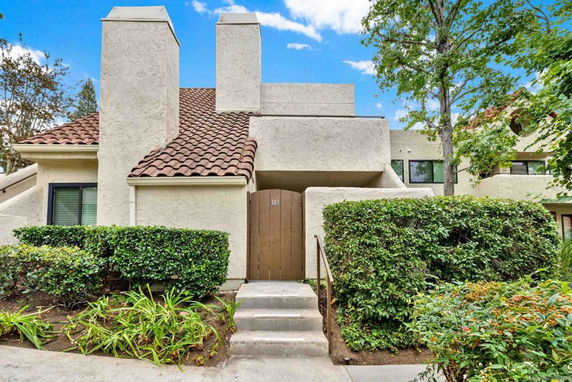 Front view of a multi-story house with tiled roof and stucco exterior.