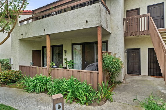 Front view of a residential building with a balcony and entrance doors.