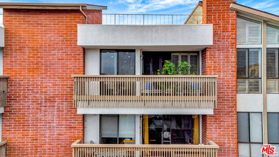 Front view of a multi-story building with brick facade and balconies.