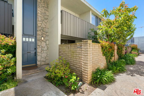 Front view of a two-story house with a stone facade and a wooden door.