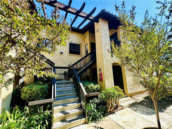 Front view of a two-story building with stairs and trees.