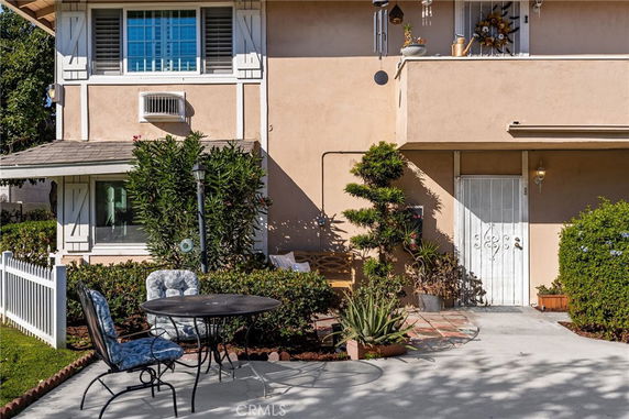 Front view of a two-story house with a small patio area and decorative plants.