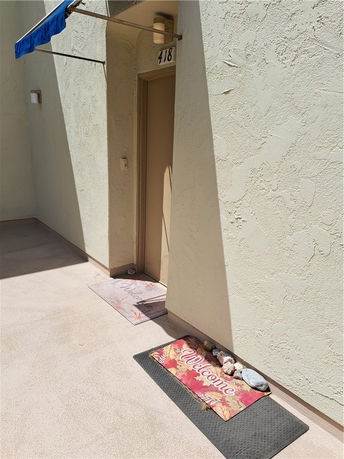 Exterior view of a building entrance with a door labeled 418 and a welcome mat.