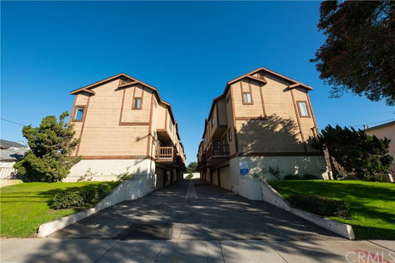 Front view of two wooden multi-story buildings facing each other with a driveway in between.