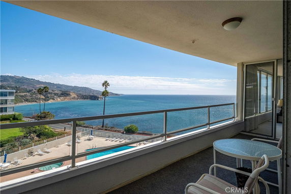 A balcony view overlooking the ocean with surrounding cliffs and buildings.
