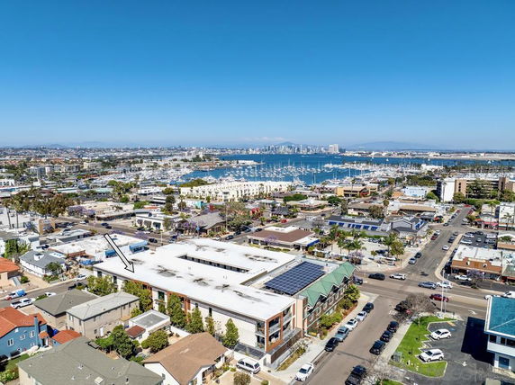 Aerial panoramic view of a coastal cityscape with buildings, roads, and a marina.