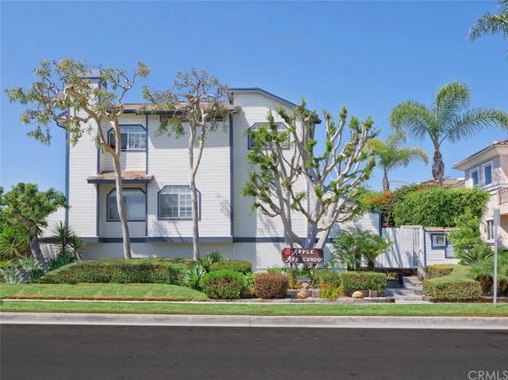 Front view of a two-story house with white siding and trees in front.