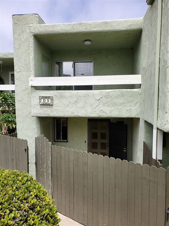 Front view of a two-story building with a balcony and fenced entrance.