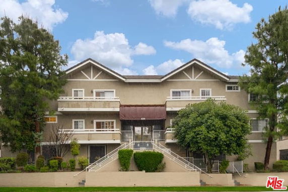 Front view of a multi-story building with balconies and sloped roofs.