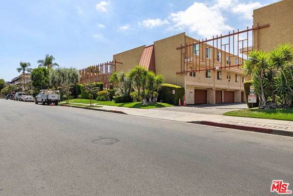 Front view of a multi-story building with garages on the ground level and wooden architectural elements.