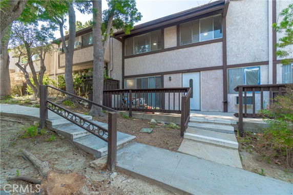 Front view of a two-story residential building with a walkway and handrails.