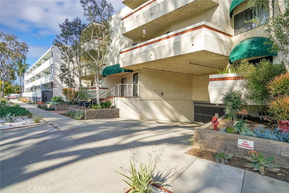 Front view of a multi-story residential building with balconies and a driveway.