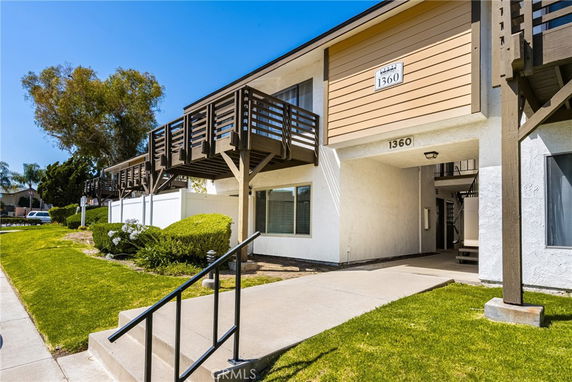 Front view of a two-story building with wooden balconies and a walkway.