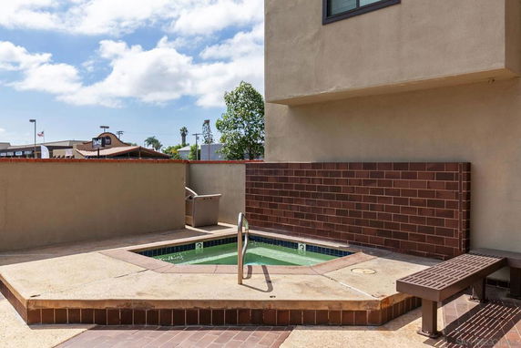 Outdoor view of a small swimming pool with a surrounding wall and bench.