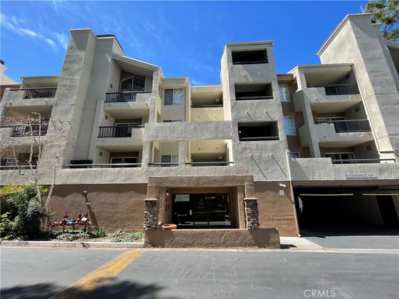 Front view of a multi-story residential building with balconies and a parking entrance.