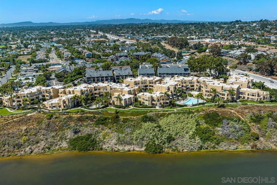 Aerial view of a large residential complex adjacent to a body of water with surrounding cityscape.