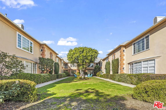 Front view of a two-story residential building complex with manicured gardens.