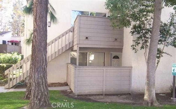 Front view of a two-story building with an exterior staircase and fenced area.