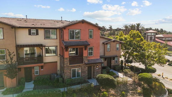 Front view of a multi-story townhouse with a balcony and brown accents.