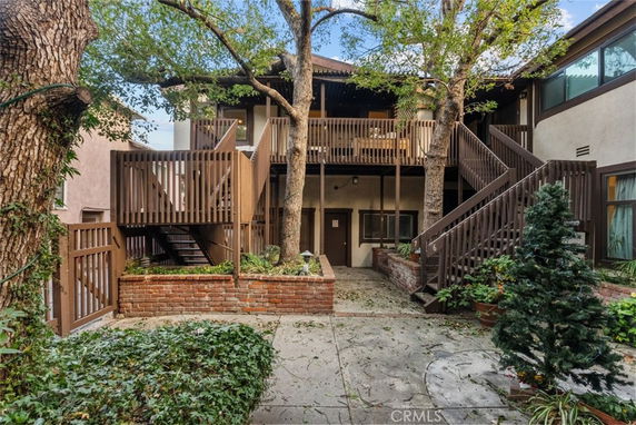 Courtyard view of a multi-story building with wooden staircases and balconies, surrounded by trees.