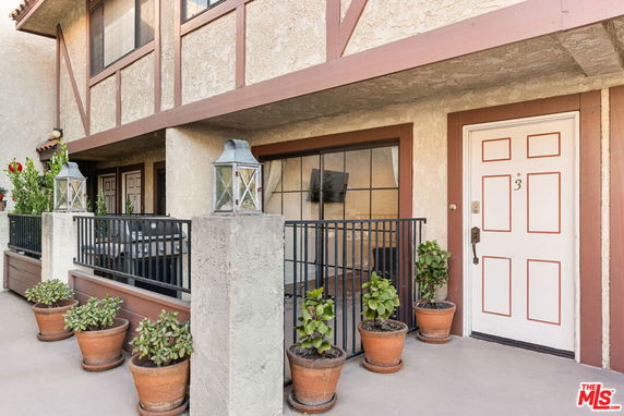 Front view of a two-story building with a balcony and decorative potted plants
