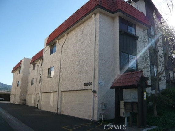 Front view of a multi-story building with garages and red-tiled roofs.