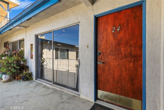 Front view of a building entrance with a wood door marked with the number 24 and a large glass window.