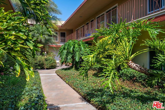 Front view of a two-story building with a walkway and lush greenery.