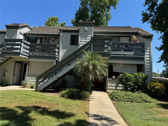 Front view of a two-story building with wooden railings and stairs leading to the upper floor.
