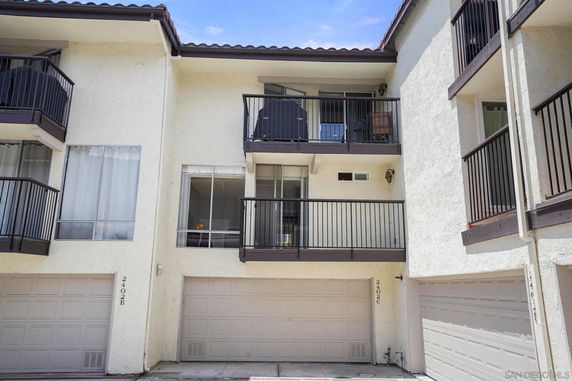 Front view of a multi-story residential building with balconies and garages.